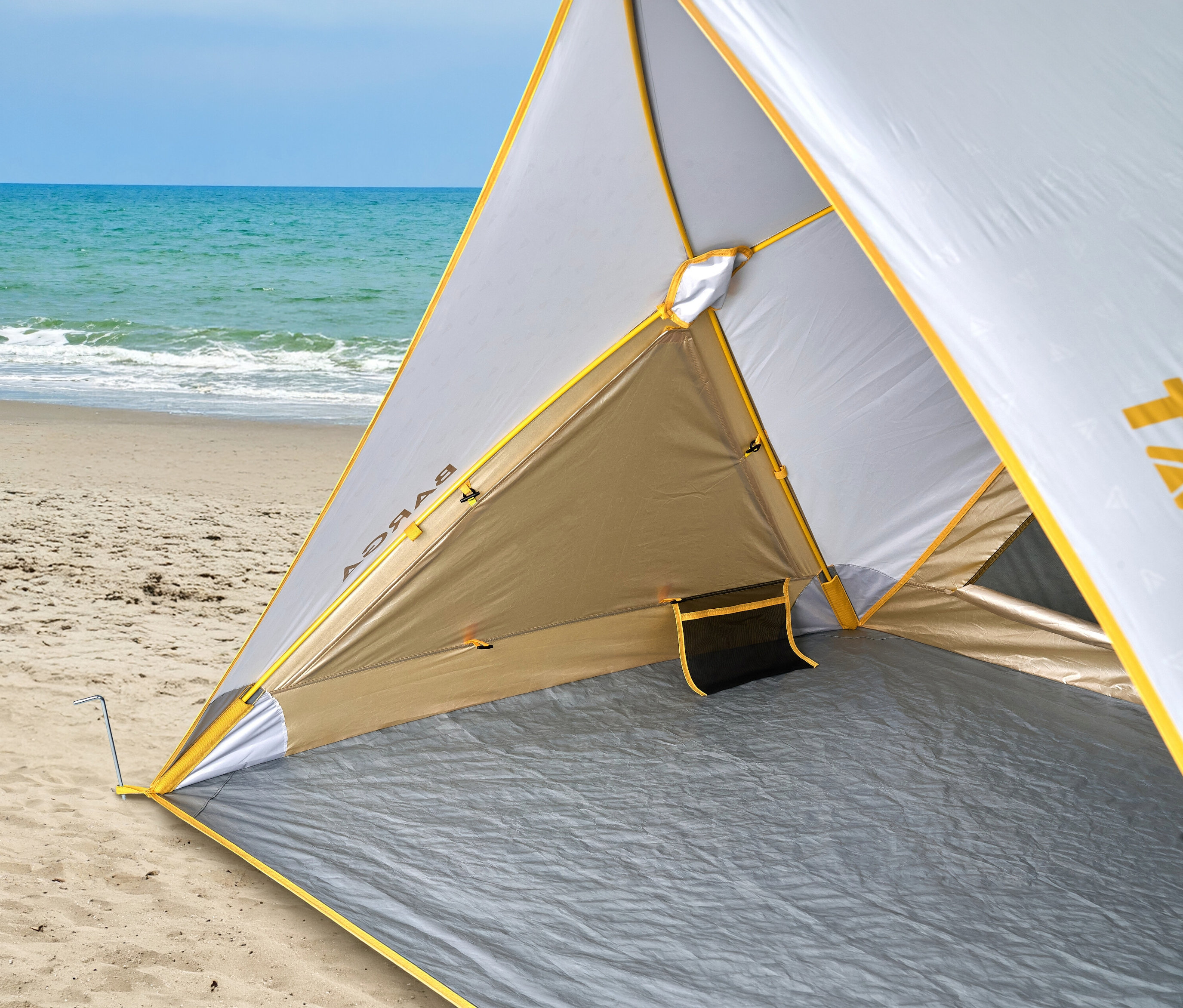 Blick ins Innere eines Strandzeltes mit gelbem Rand am Sandstrand mit Blick auf das Meer.