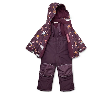 Lila Kinder-Schneeanzug und Jacke mit Einhorn-, Stern- und Regenbogenmuster liegen auf dem Boden.