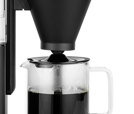 Eine Kaffeemaschine brüht Kaffee in eine Glaskanne. Der Filter ist schwarz.