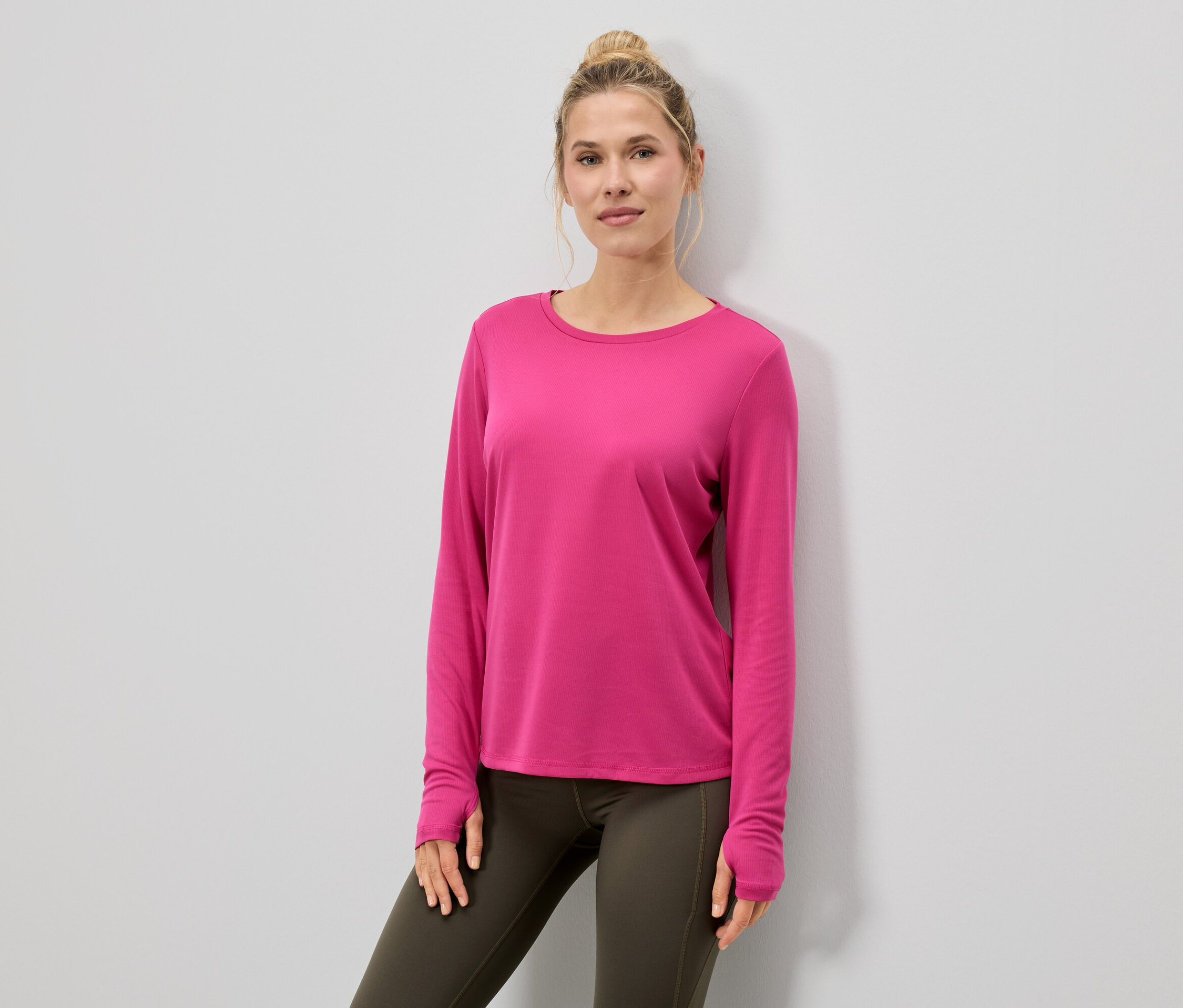 Frau trägt ein pinkes Langarmshirt und Leggings.