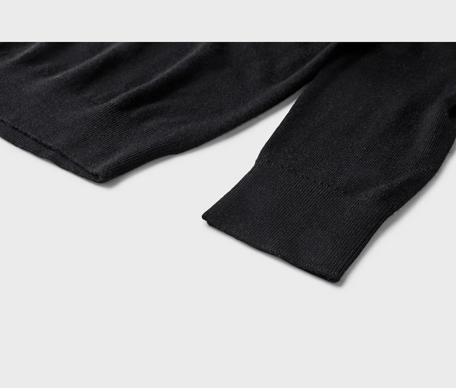 Nahaufnahme eines schwarzen Strickkleidungsstücks, das einen gerippten Ärmelbund und einen gerippten Saum zeigt.