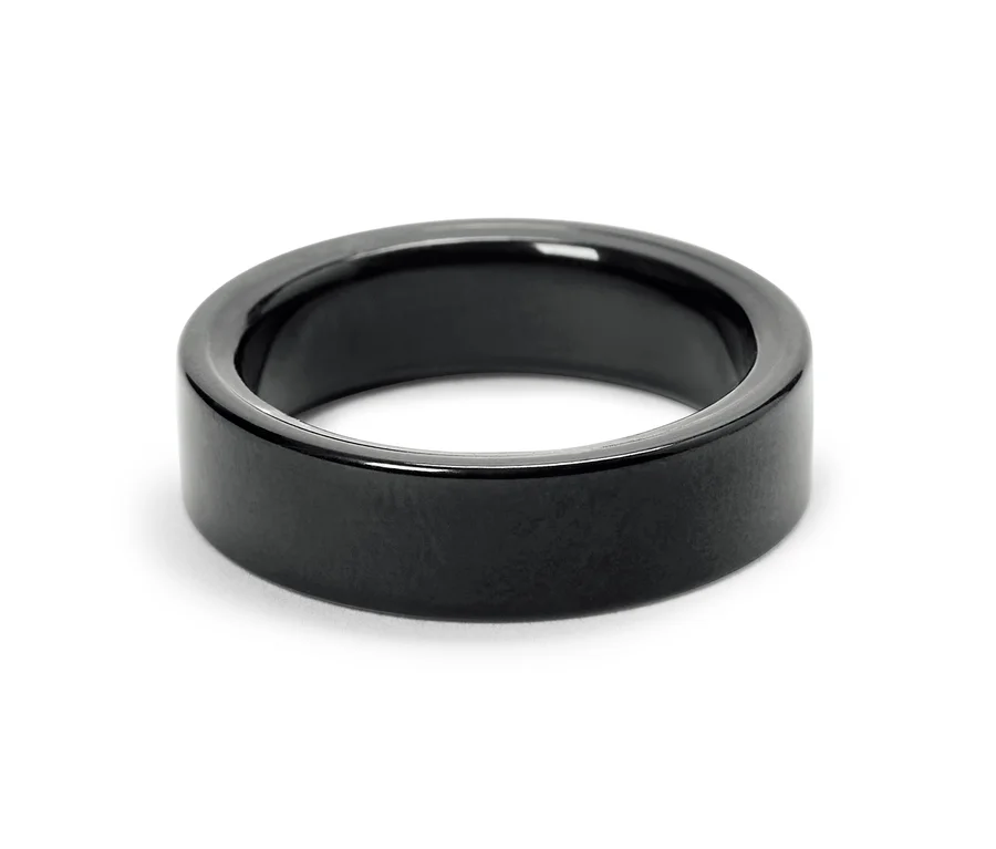 Detailaufnahme eines glänzenden, schwarzen Rings auf weißem Hintergrund.