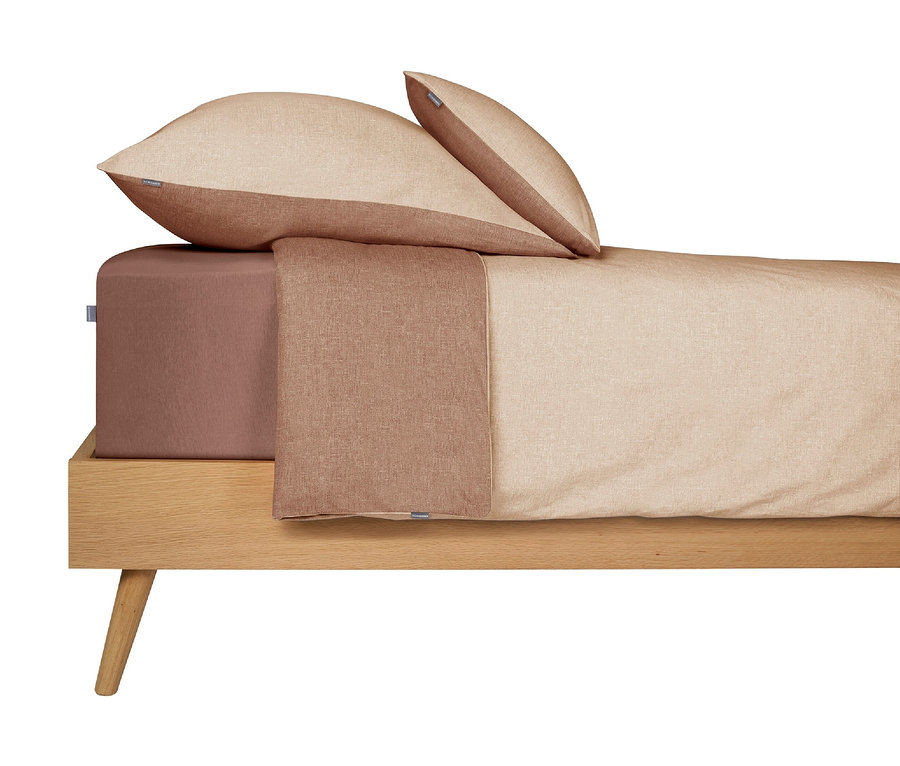 Ein Bett mit SCHIESSER Renforcé-Bettwäsche Doubleface in Sandfarben und Braun. Die Kissen und die Decke sind zweifarbig sandfarben und braun, das Spannbettlaken ist einfarbig braun. Das Bett hat einen hellen Holzrahmen mit schrägen Beinen.