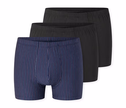 Drei Herren-Boxershorts; vorne eine dunkelblaue mit weißen und roten Streifen, dahinter zwei dunkelgraue.