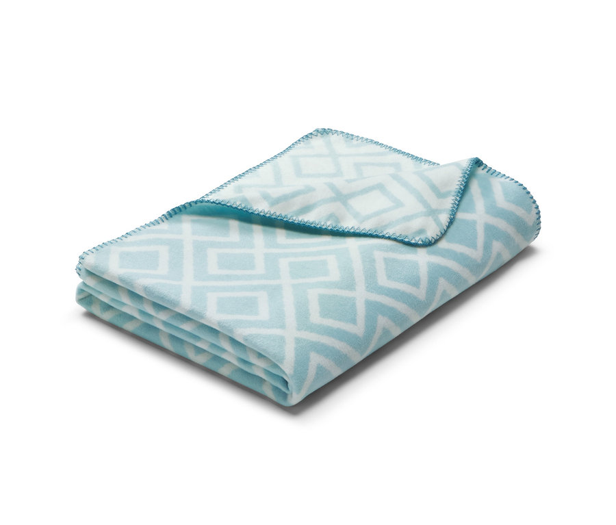 Eine gefaltete Plaiddecke mit geometrischem Muster.