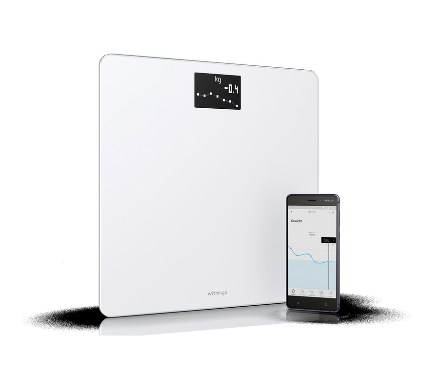 Weiße Withings Körperanalyse-Waage »Body« neben einem Smartphone, das ein Gewichtsverlaufsdiagramm anzeigt.