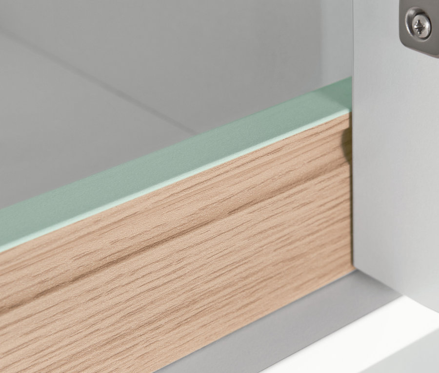 Detailansicht eines schmalen Badezimmer-Hochschranks mit Holzschublade und grünem Rand.