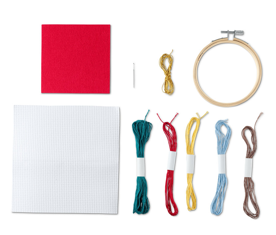 Stick-Set beinhaltet ein rotes und ein weißes Stoffquadrat, eine Nadel, goldenes Garn, einen Stickrahmen und farbige Garne.
