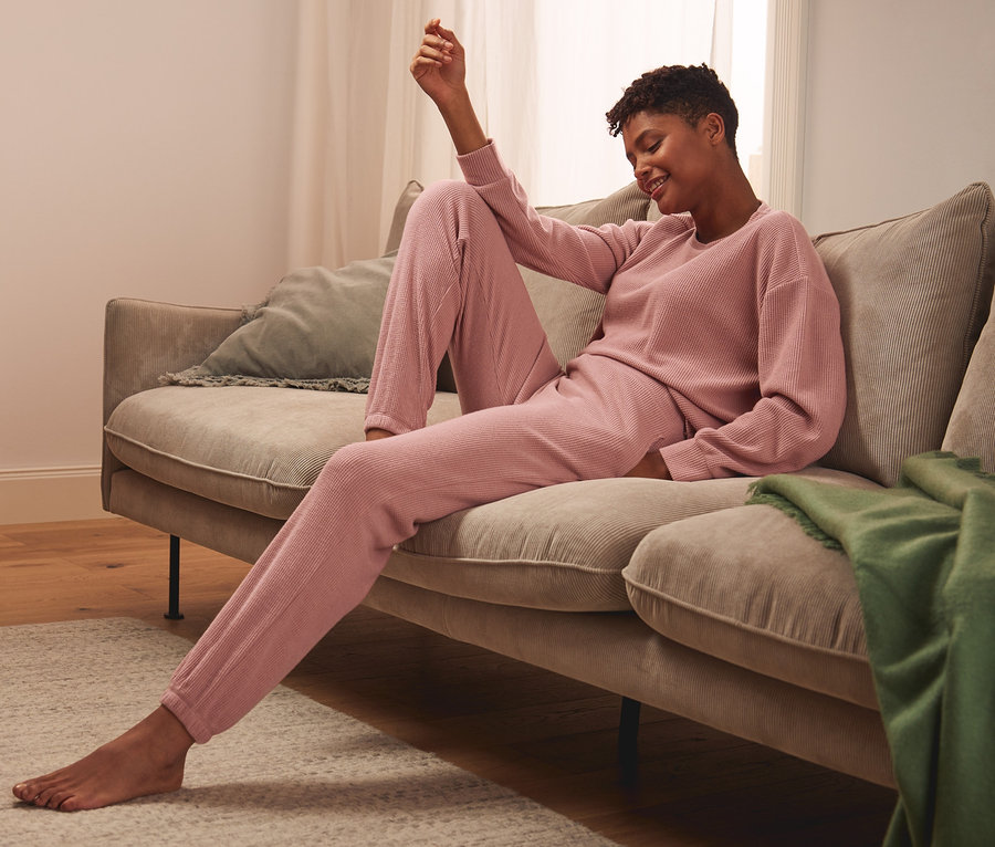 Frau sitzt auf Sofa und trägt eine Loungehose mit Waffelmuster.