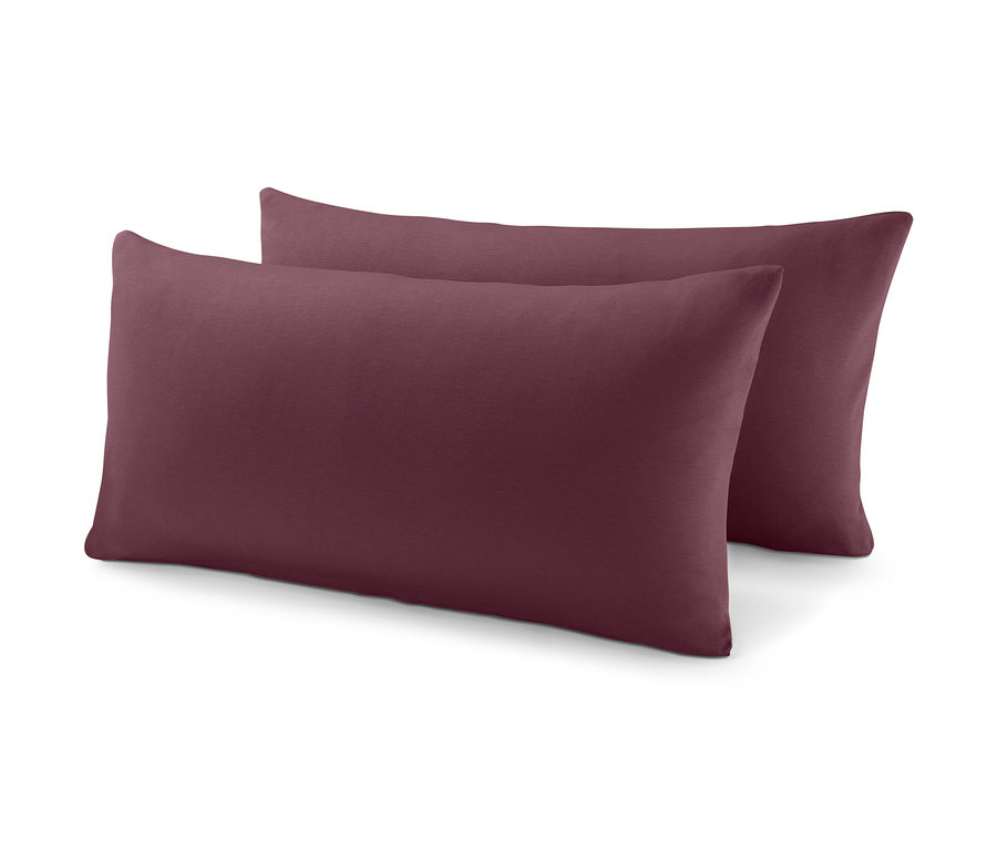 Zwei burgunderrote Kissen liegen übereinander.
