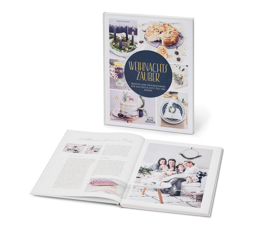 Zwei Bücher: eines geschlossen mit Bildern von Adventskranz, Gebäck und Torte, und eines geöffnet mit einem Foto einer Familie im Wohnzimmer. Zu sehen ist auch das Buch »Weihnachtszauber«.