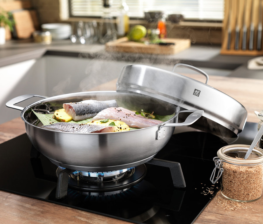 Fisch und Ananasscheiben werden im ZWILLING® Plus Räucher-Set auf einem Induktionskochfeld zubereitet.