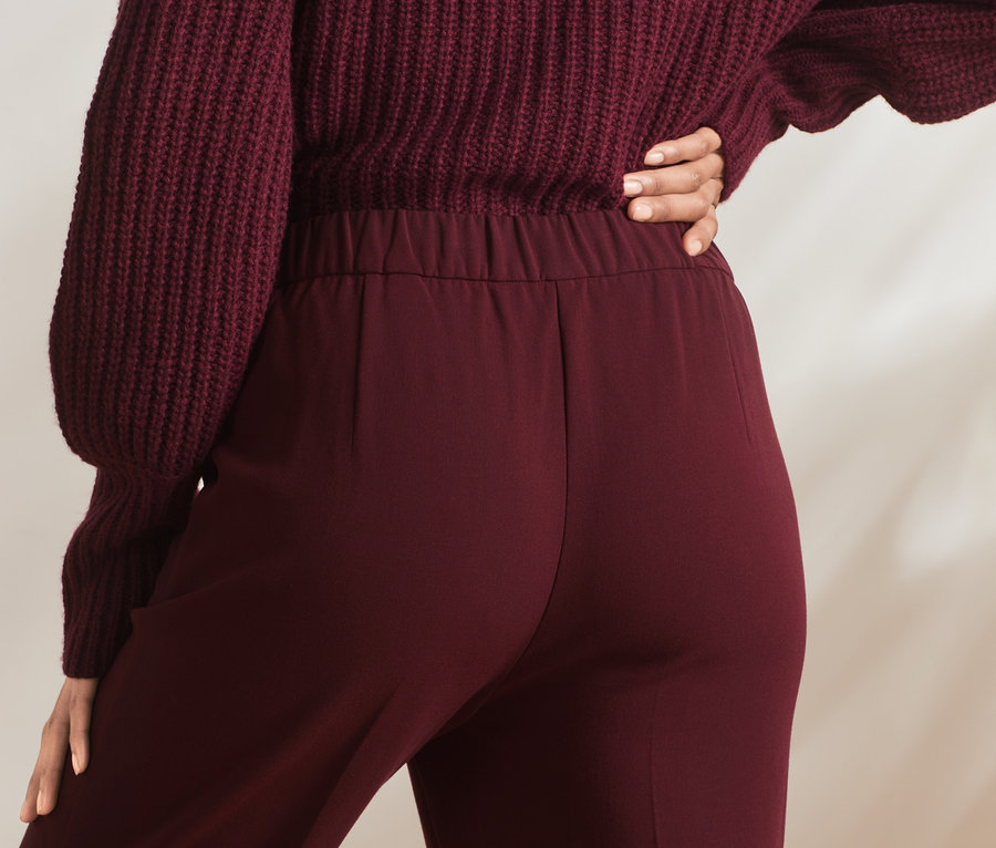 Person trägt eine Stoffhose und einen Pullover.