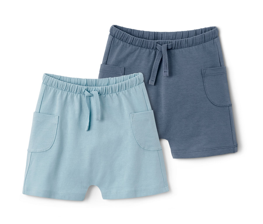 Zwei Baby-Jerseyshorts aus Bio-Baumwolle, eine hellblau, die andere blau, liegen nebeneinander.