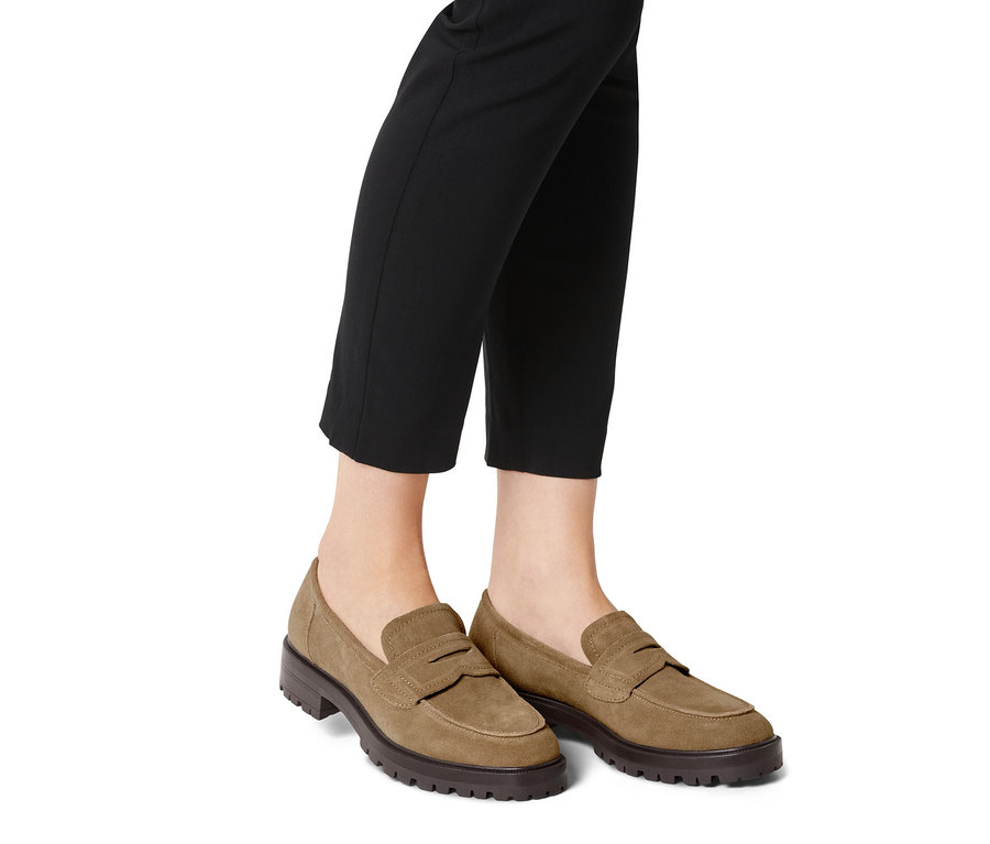 Beine in schwarzen Hosen und Veloursleder-Loafer.