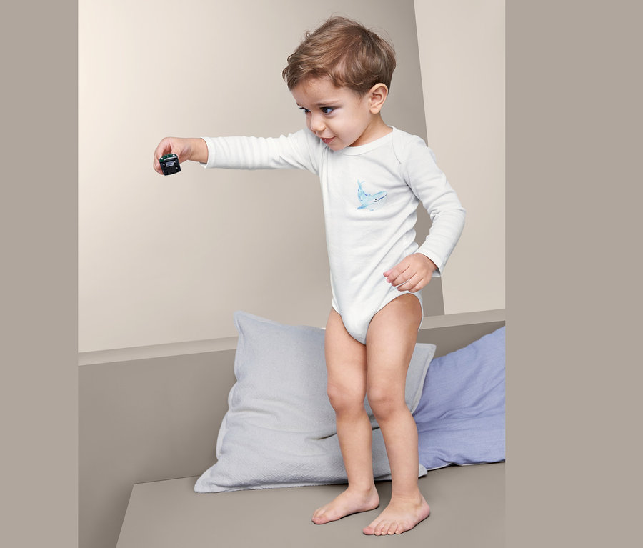 Kleiner Junge hält Spielzeugauto und trägt 5 Baby Baumwoll-Bodys.