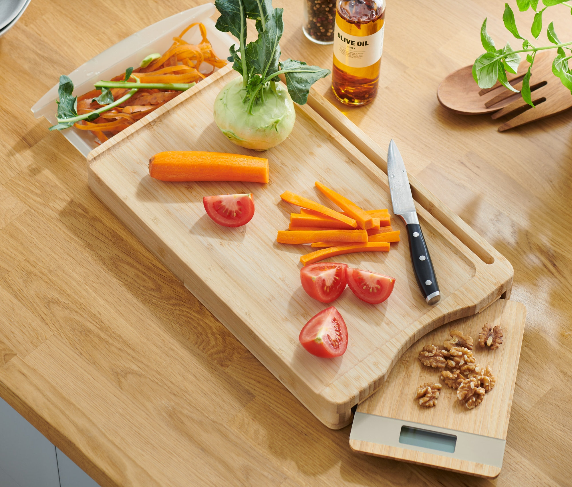 Schneidebrett mit herausnehmbarer Küchenwaage aus Bambus mit geschnittenem Gemüse und Messer.