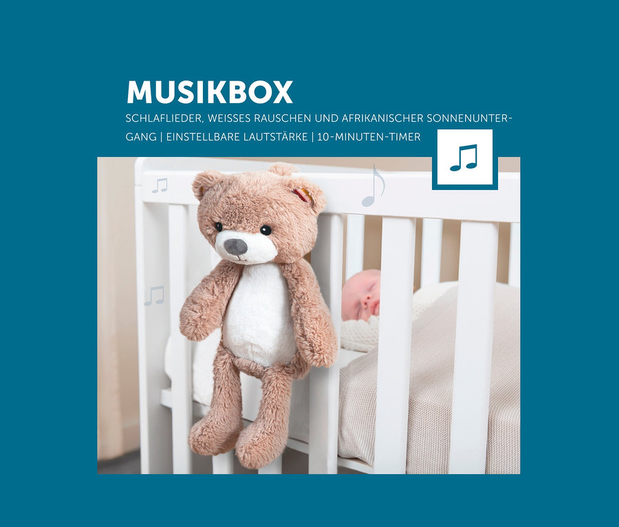Brauner Teddybär Zazu Nachtlicht »Brody der Bär« hängt an einem weißen Kinderbett, in dem ein Baby schläft.