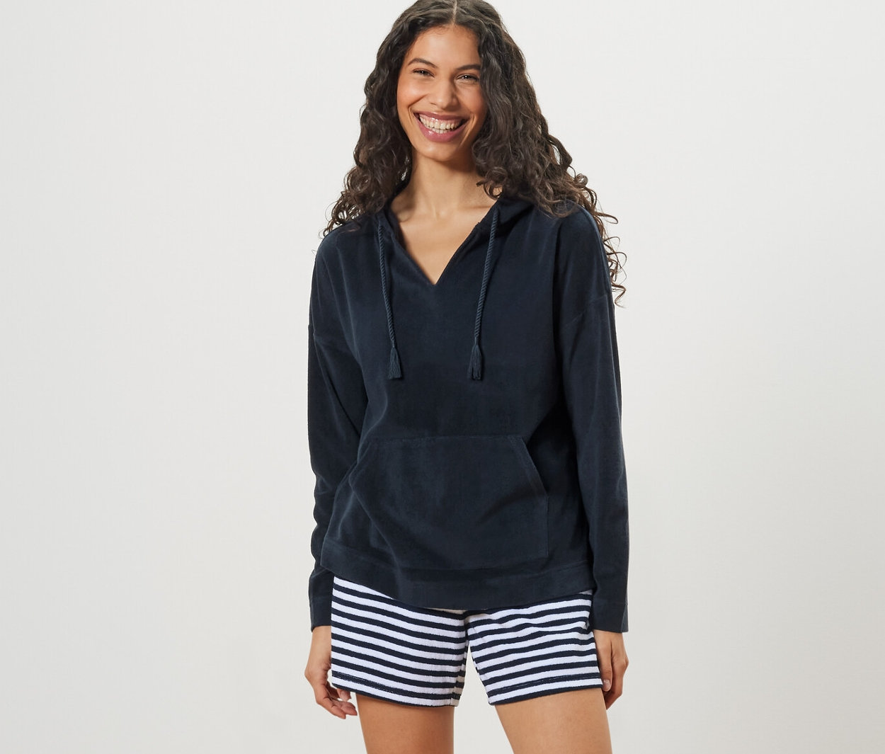 Frau trägt einen Frottee-Hoodie und gestreifte Shorts.