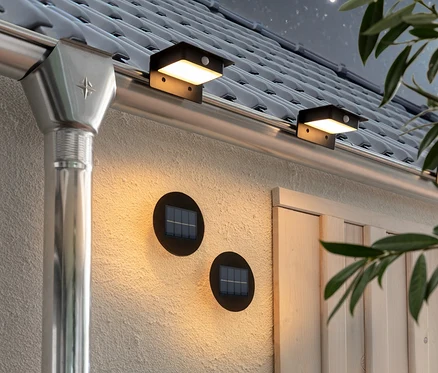 Zwei Solar-Wand-und-Stufenlichter und drei Solar-Dachrinnenleuchten sind an der Wand und der Dachrinne des Hauses befestigt.