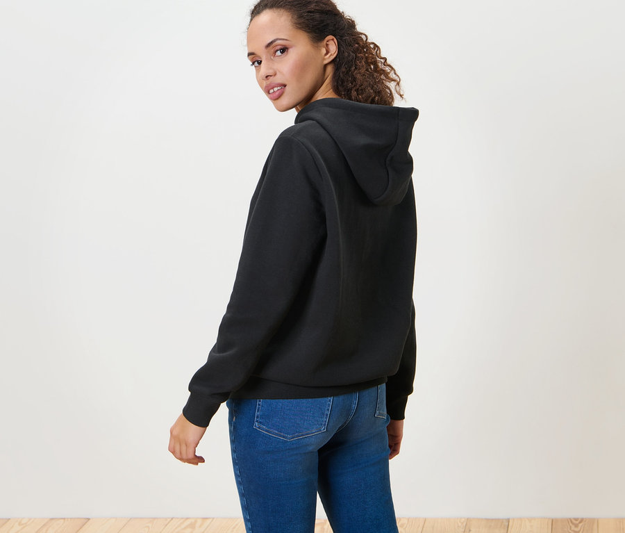 Frau blickt über die Schulter und trägt einen schwarzen Hoodie.