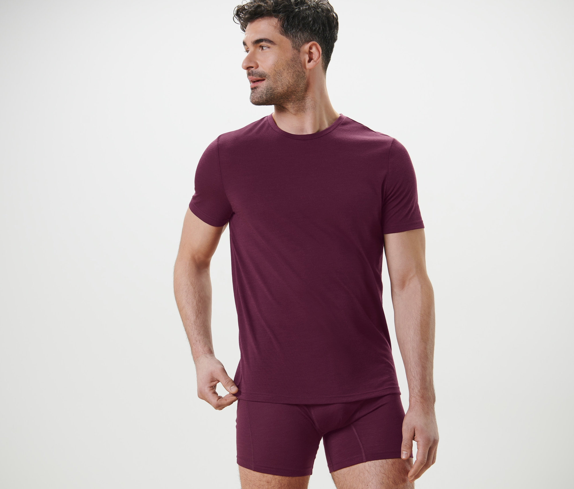 Mann posiert in einem burgunderroten Funktionsshirt mit Merinowolle und Boxershorts.