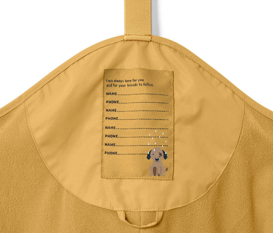 Detail einer gelben Kinder-Thermo-Regenhose mit Etikett für Name und Telefonnummer.