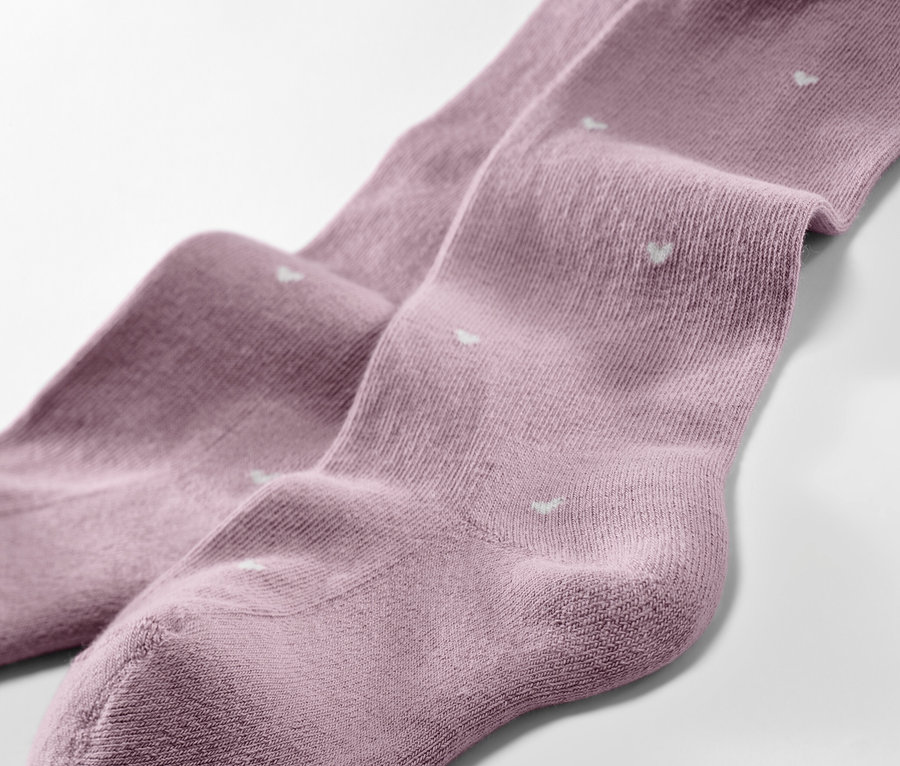 Detailaufnahme von drei Kinder-Strumpfhosen mit Herzchenmuster.