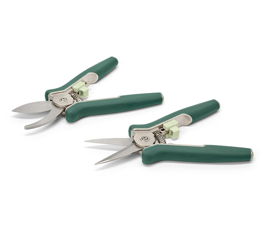 Zwei Mini-Pflegescheren liegen auf einer weißen Fläche.