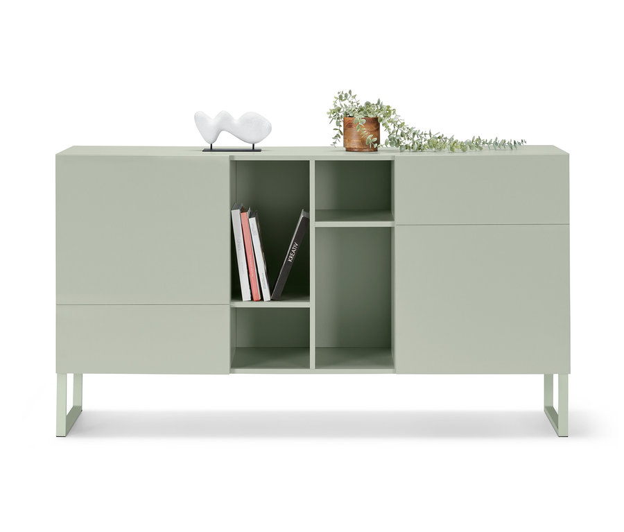 Ein hellgrünes, halboffenes Sideboard mit Kufen, Büchern und Deko.