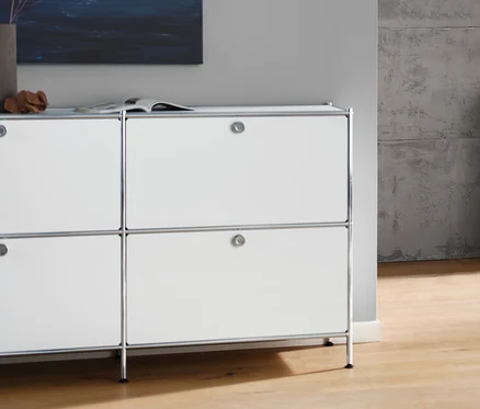 Wohnzimmer mit weißem Sideboard »CN3« mit 6 Klappen, anthrazitfarbenem 3-Sitzer-Sofa, weißer Tischleuchte mit Textilschirm und weißem Couchtisch mit Rollen »CN3«.