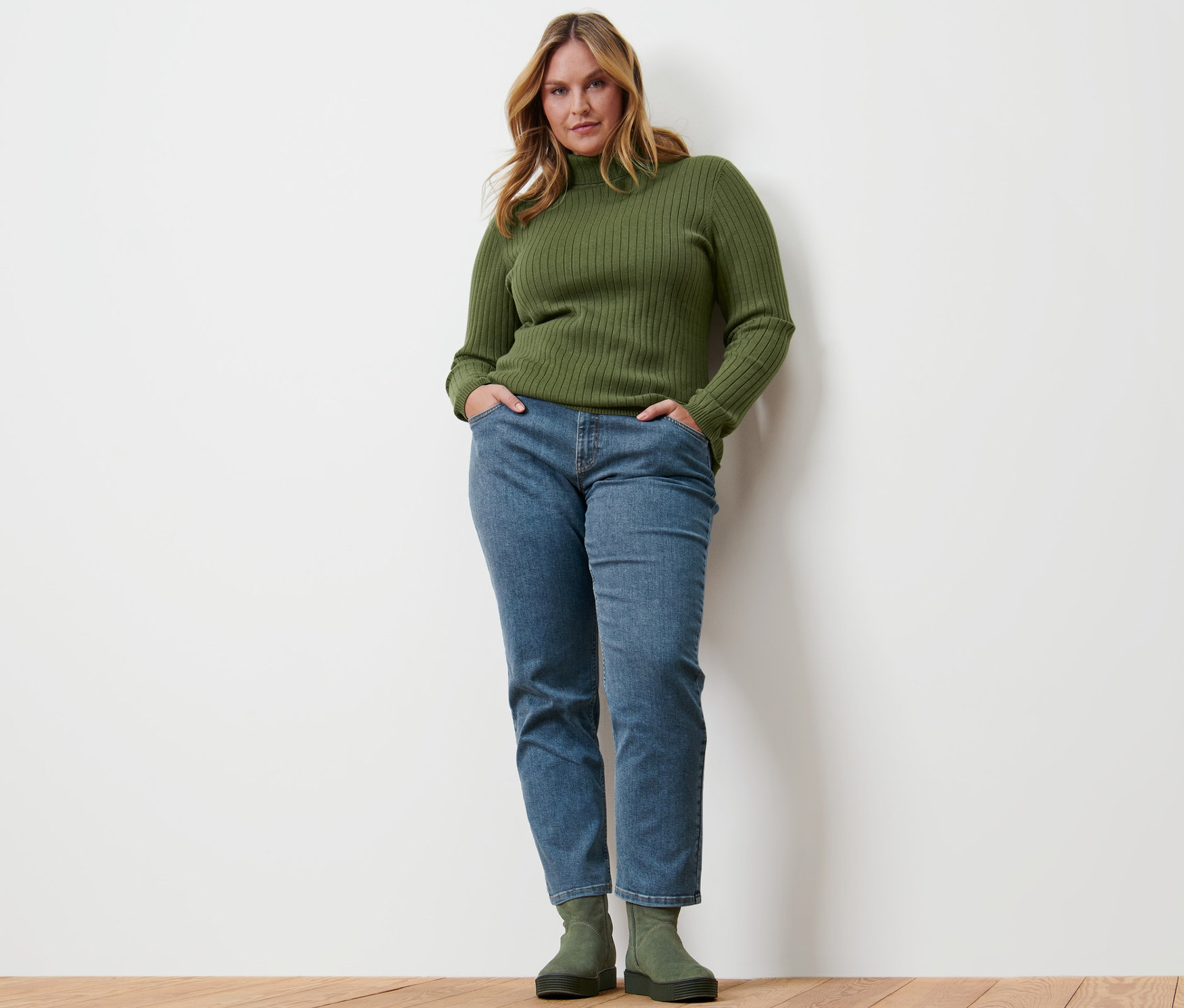 Frau posiert in geripptem Rollkragenpullover, Straight-Denim »Fit Juna«, midblue, und Veloursleder-Boots.