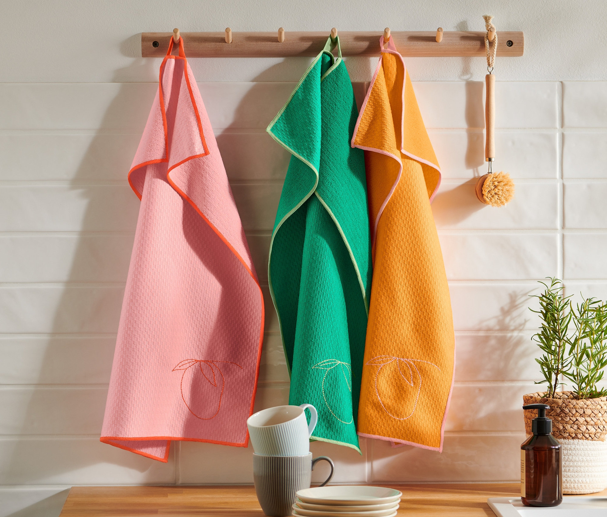 Drei Geschirrtücher hängen an einer Holzleiste.