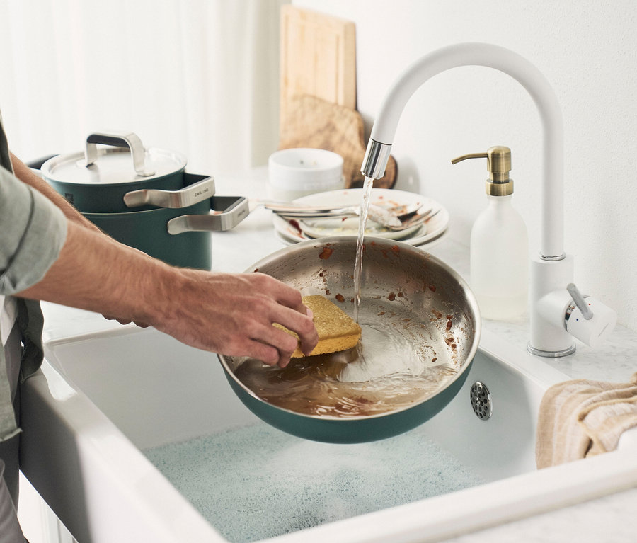 Mann spült eine Pfanne aus dem 5-teiligen ZWILLING PURE Edelstahl-Kochgeschirr-Set in der Spüle.