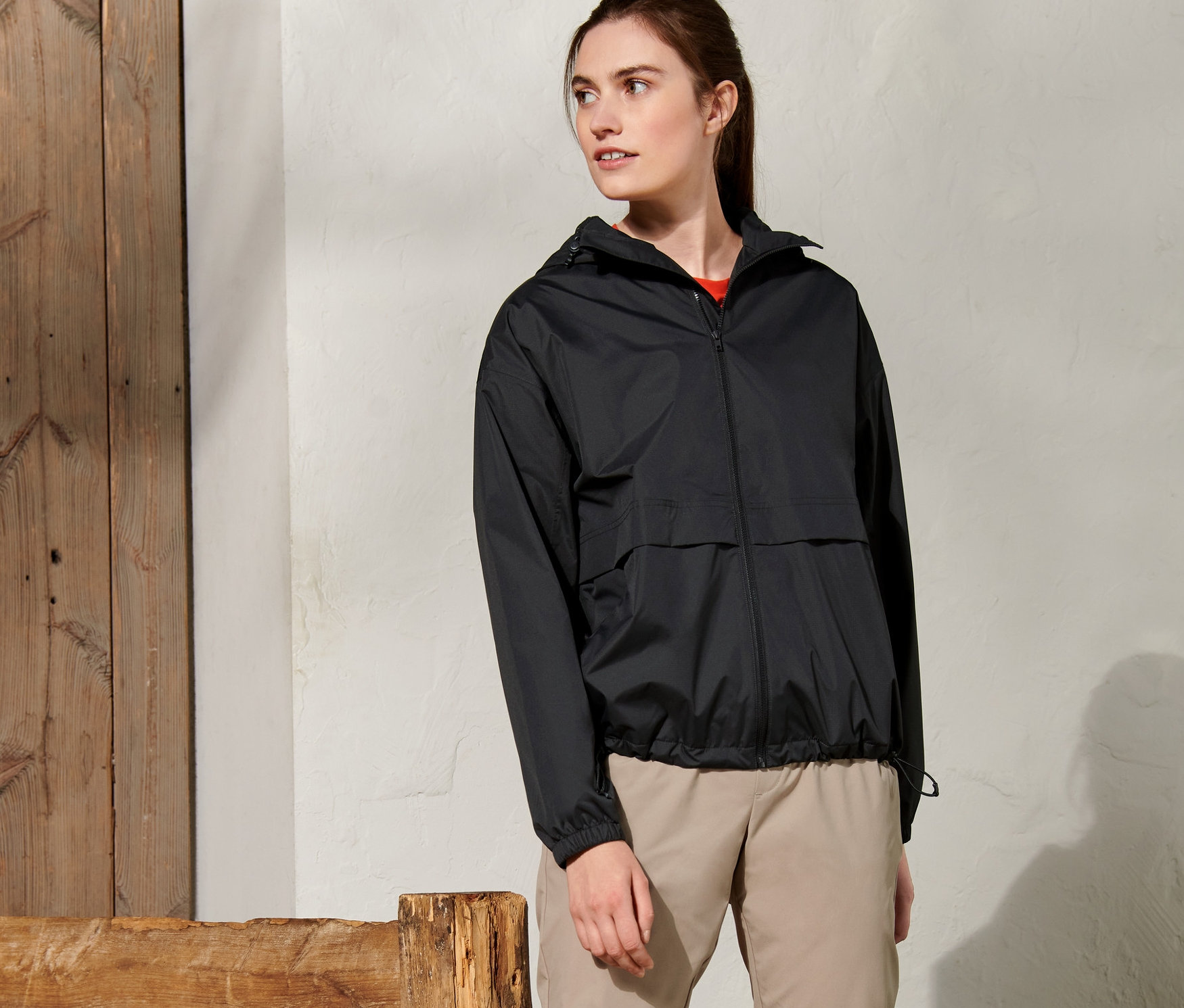 Frau steht draußen und trägt eine schwarze Regenjacke.