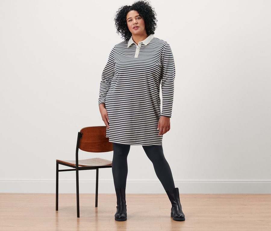 Frau posiert in gestreiftem Sweatkleid mit Polokragen und 2 Paar blickdichten Strumpfhosen, schwarz.