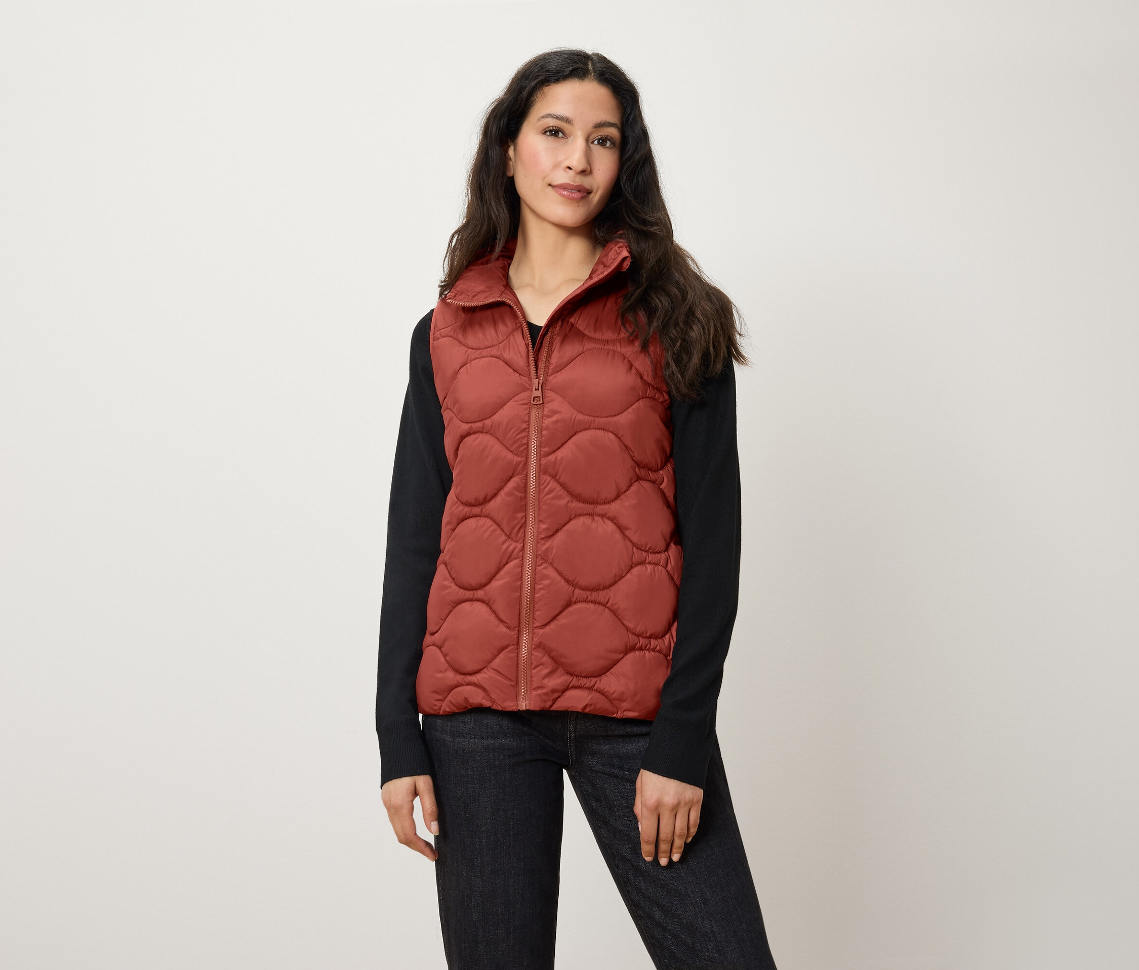 Frau trägt eine gesteppte Weste in Rostfarbe.