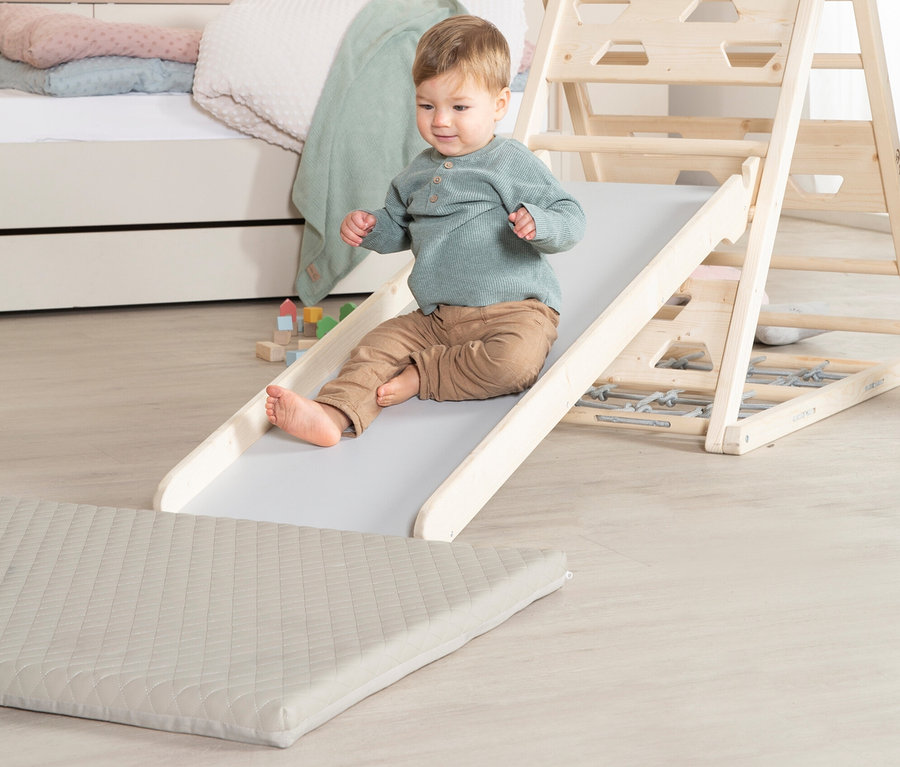 Ein Kind rutscht eine Rutsche runter, daneben liegt die roba Spielmatte »Luxe«.