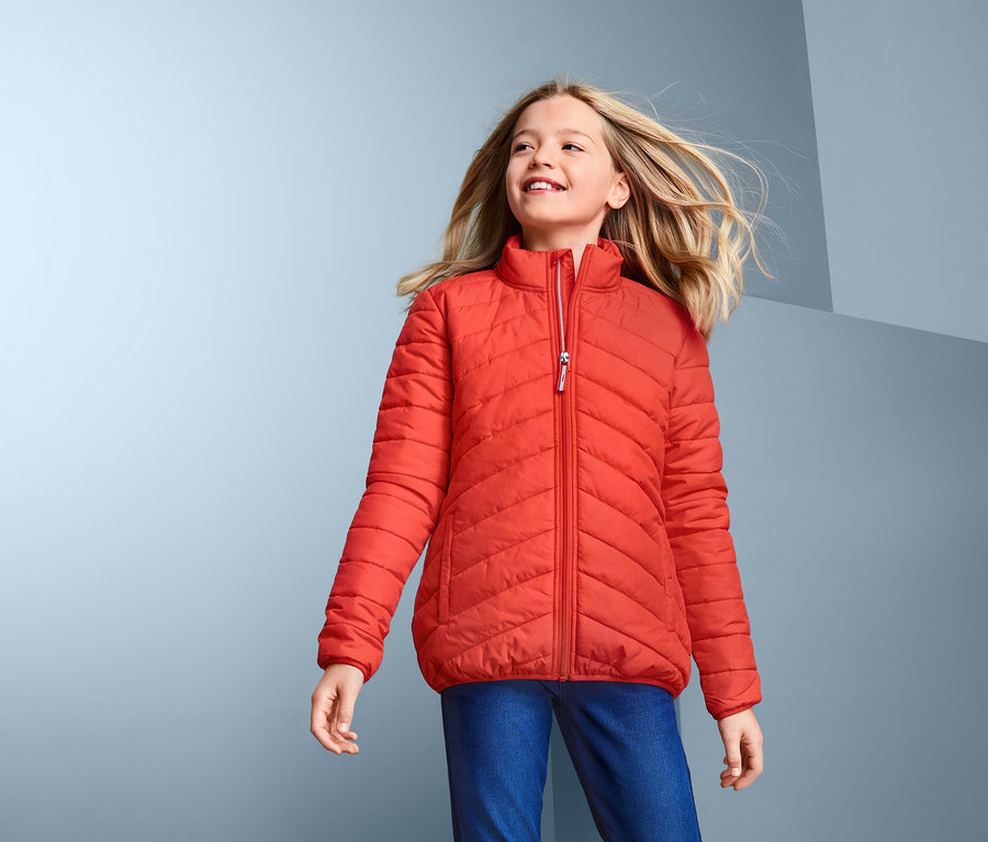 Mädchen trägt eine Steppjacke mit recyceltem Material und schaut nach oben.