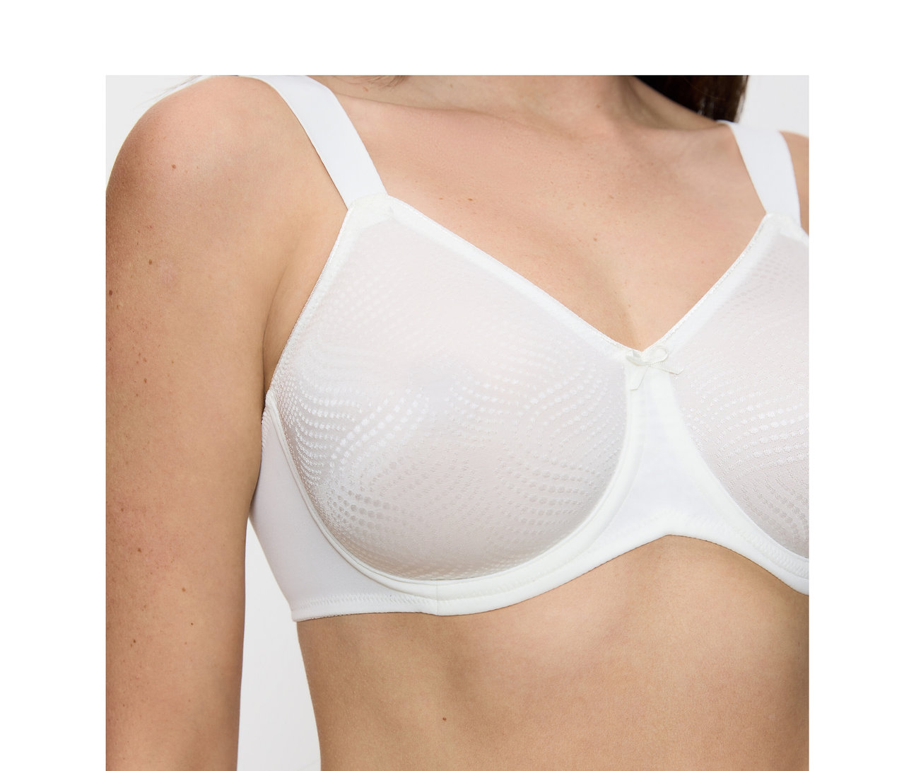 Frau trägt einen vanillefarbenen Triumph Essential »Minimizer W X« BH mit gemusterten Cups und kleiner Schleife.