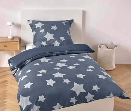 Blaue Bettwäsche mit Sternen auf einem Bett.