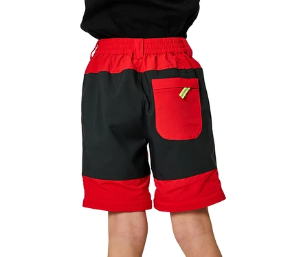 Kind von hinten in rot-schwarzen Jako-O Shorts. Die Shorts haben einen roten Bund, eine rote Gesäßtasche mit gelbem Detail und rote Beinabschlüsse.
