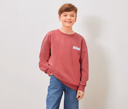 Junge posiert in rotem Kinder-Sweatshirt.