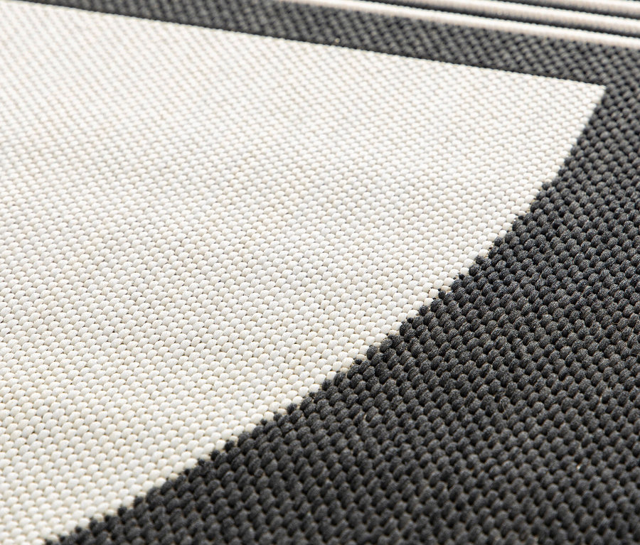 Detailaufnahme eines Outdoor-Teppichs »Zen Lines« mit einem geometrischen Muster in Grau- und Weißtönen.