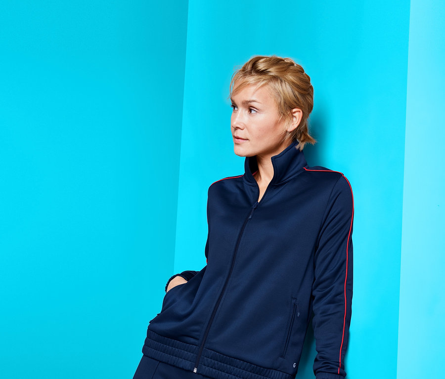 Frau posiert in marineblauer Sportjacke.