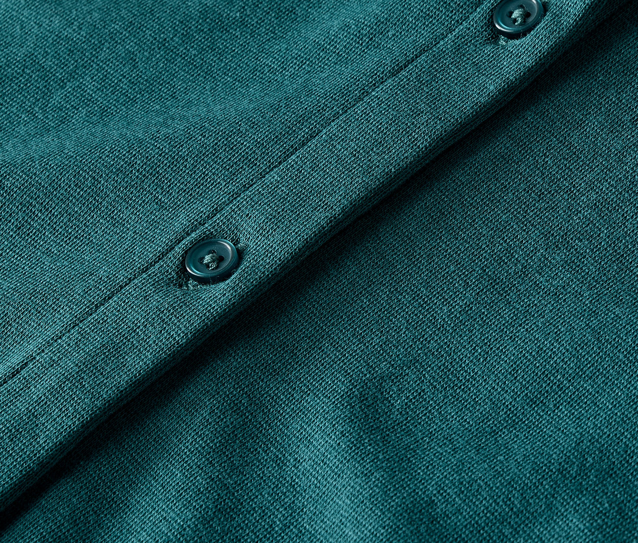 Detailaufnahme eines grünen Strickcardigans mit Knöpfen.