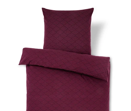 Weinrote Bettwäsche mit geometrischem Muster und Kopfkissen.