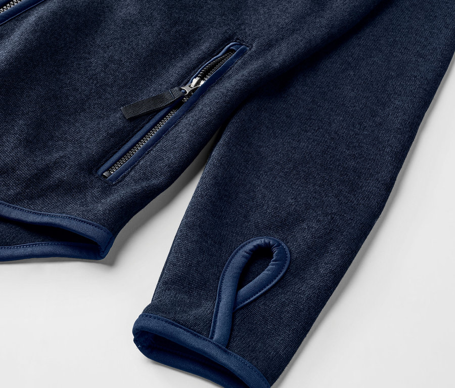 Detail einer Strickfleece-Jacke, navy, mit Daumenloch und Reißverschlusstasche.