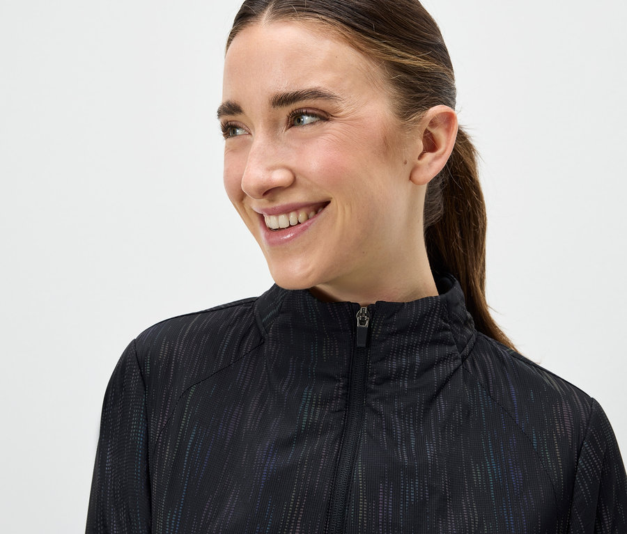 Porträt einer lächelnden Frau in einer schwarzen Reissverschlussjacke.