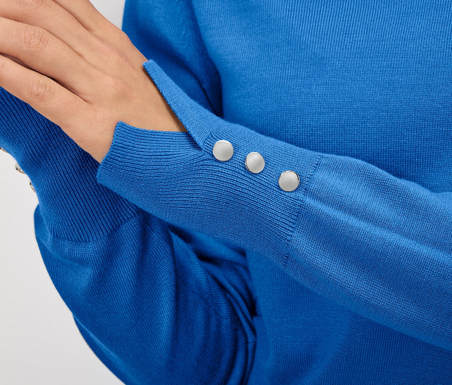 Detailaufnahme eines blauen Damenpullovers mit Knöpfen am Ärmel.
